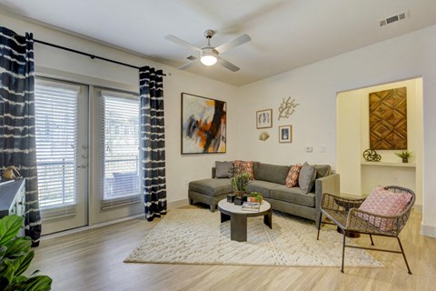 a living room with a ceiling fan and sliding glass doors